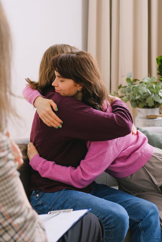 Two women embrace during a therapy session, symbolizing support and friendship.