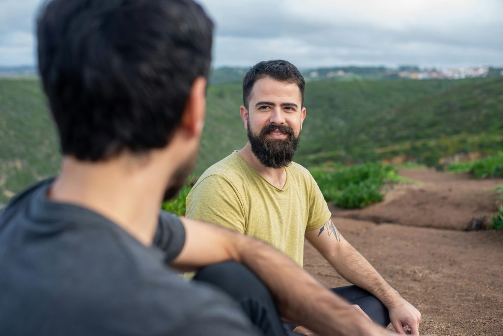 Two men enjoying a tranquil moment outdoors in the lush landscape of Portugal, embracing relaxation and wellbeing.