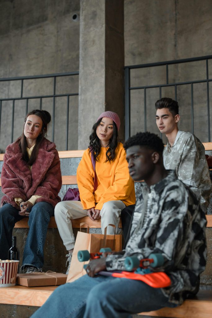 A diverse group of young adults sitting together, showcasing modern fashion and friendship.