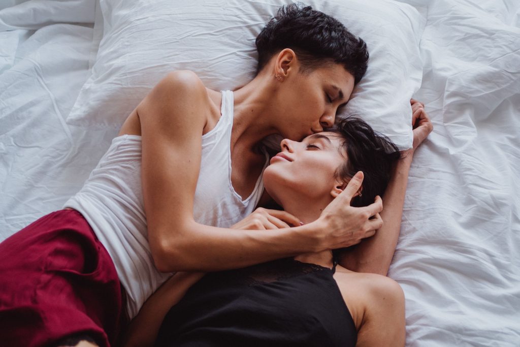 A romantic scene of a same-sex couple embracing in a peaceful, intimate setting at home.
