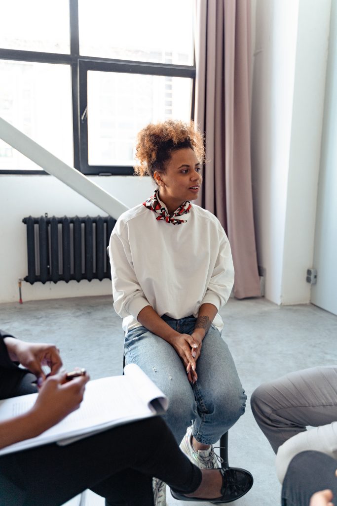 pexels photo 7579311 7579311 A woman participates in a group therapy session indoors, engaging with peers.