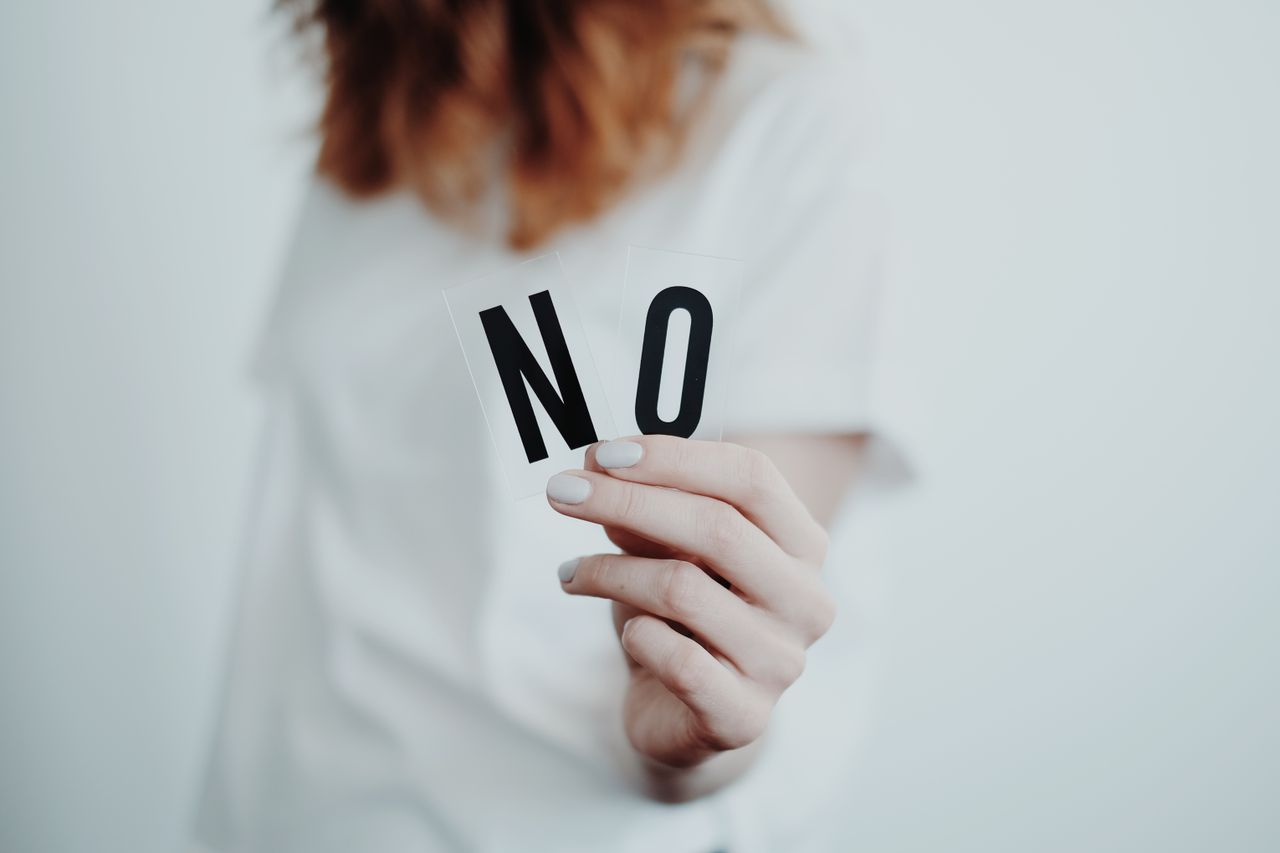 How to Set Healthy Boundaries for Your Mental Health Close-up of a person holding a "No" sign, symbolizing rejection or disagreement.