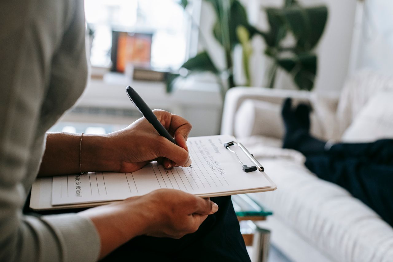 A Complete Guide to Partial Hospitalization Programs Unrecognizable ethnic female therapist taking notes on clipboard while filling out form during psychological appointment with anonymous client lying on blurred background