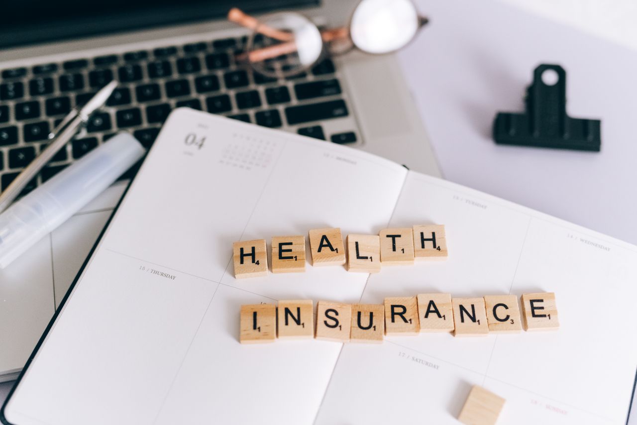 Guide to Insurance Coverage for PHP and IOP Treatment Close-up of Scrabble tiles spelling 'Health Insurance' on a planner with a laptop.