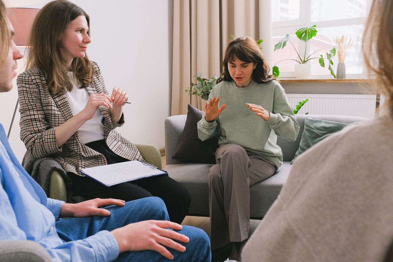 How Therapy and IOP Treat Emotional Dysregulation Women in casual clothes sitting on sofa and speaking during group psychotherapy session in cozy office
