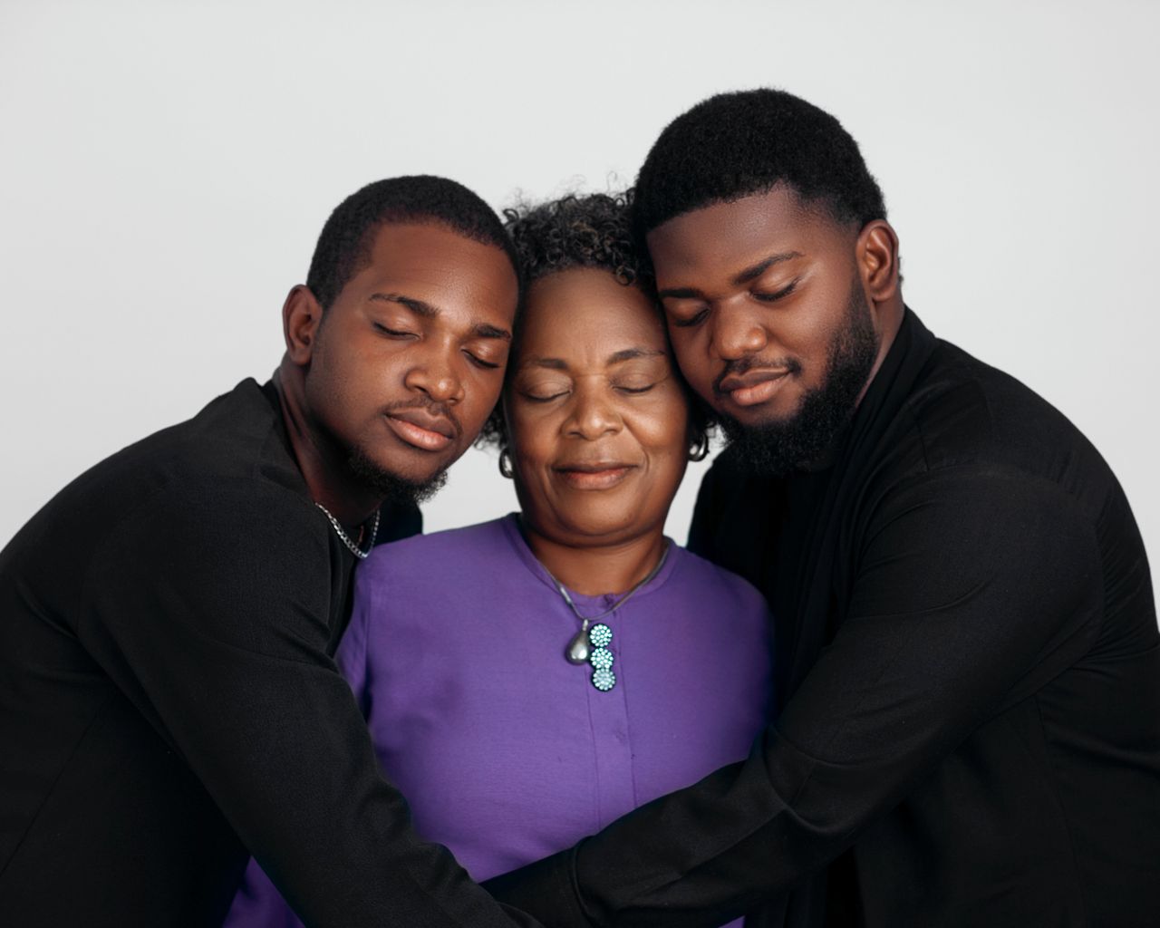 How Family Therapy Aids Gambling Addiction Recovery Two young men lovingly embrace an older woman in a warm family portrait.