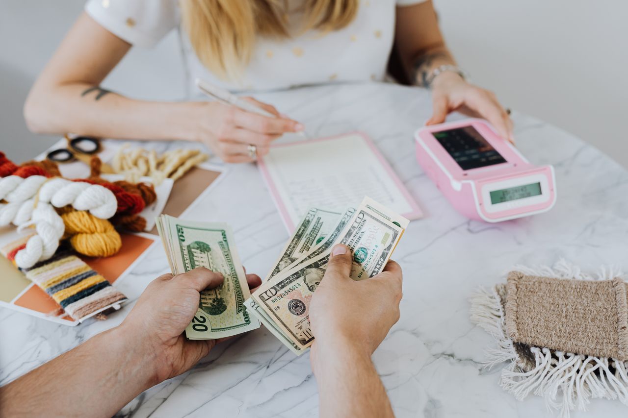 Spotting Financial Impulsivity and Gambling Addiction Two people handling cash and budgeting with a calculator and notebook at a table.