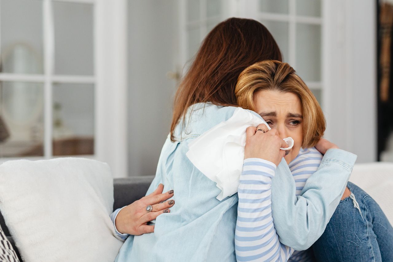 How to Support Loved Ones in Gambling Addiction Recovery Two women hugging, offering comfort and support in a cozy living room setting.